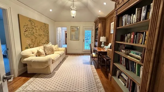 A living room with seating, a patterned rug, and built-in bookshelves.