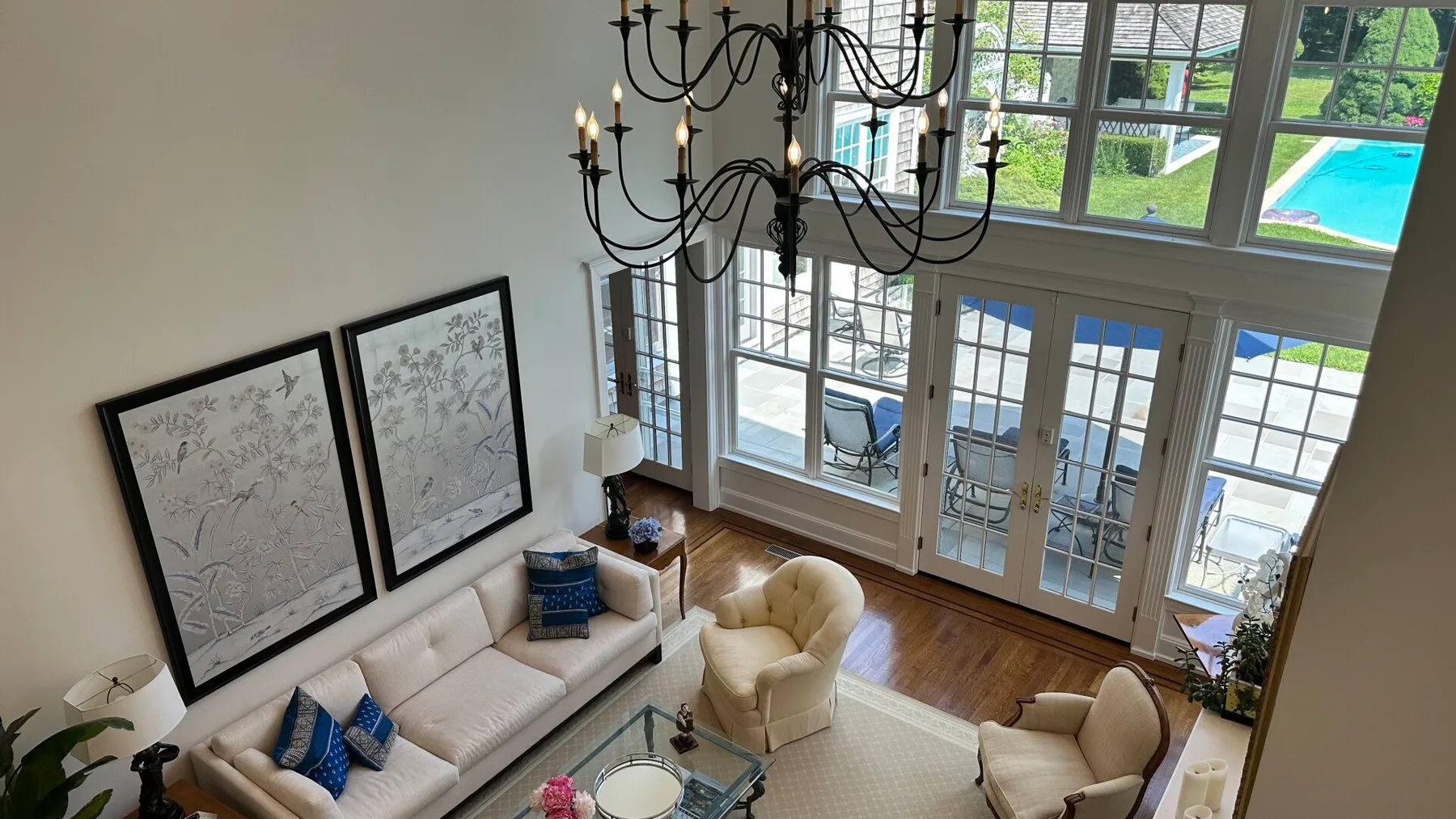 A bright living room with seating, large windows, and a view of a pool.
