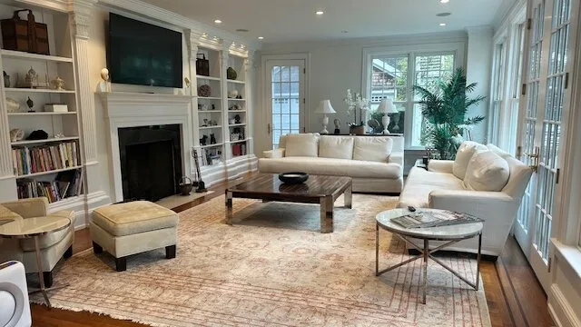 A bright living room with white seating, built-in shelves, and a fireplace.