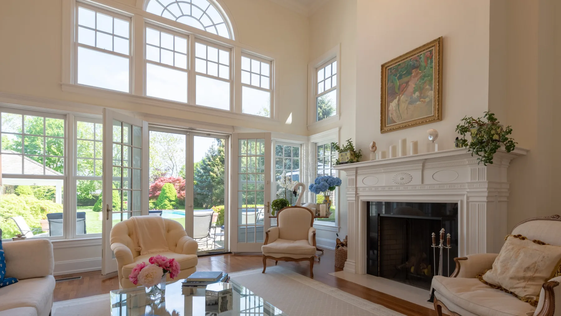 A bright living room with tall windows, seating, and a fireplace.