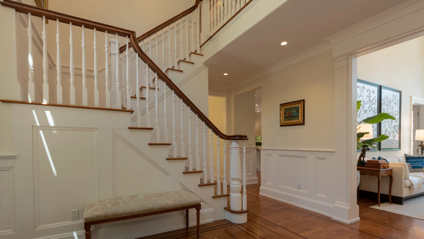 A bright interior staircase with white railings and a wooden handrail.