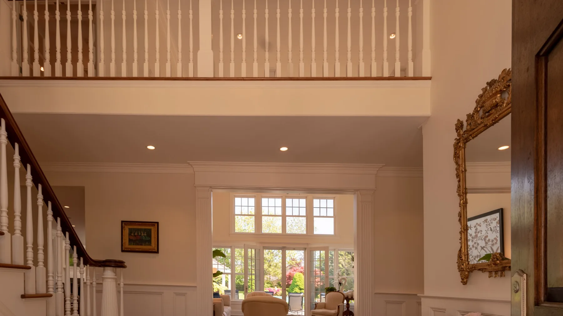 A bright interior hall with a staircase and large windows overlooking greenery.