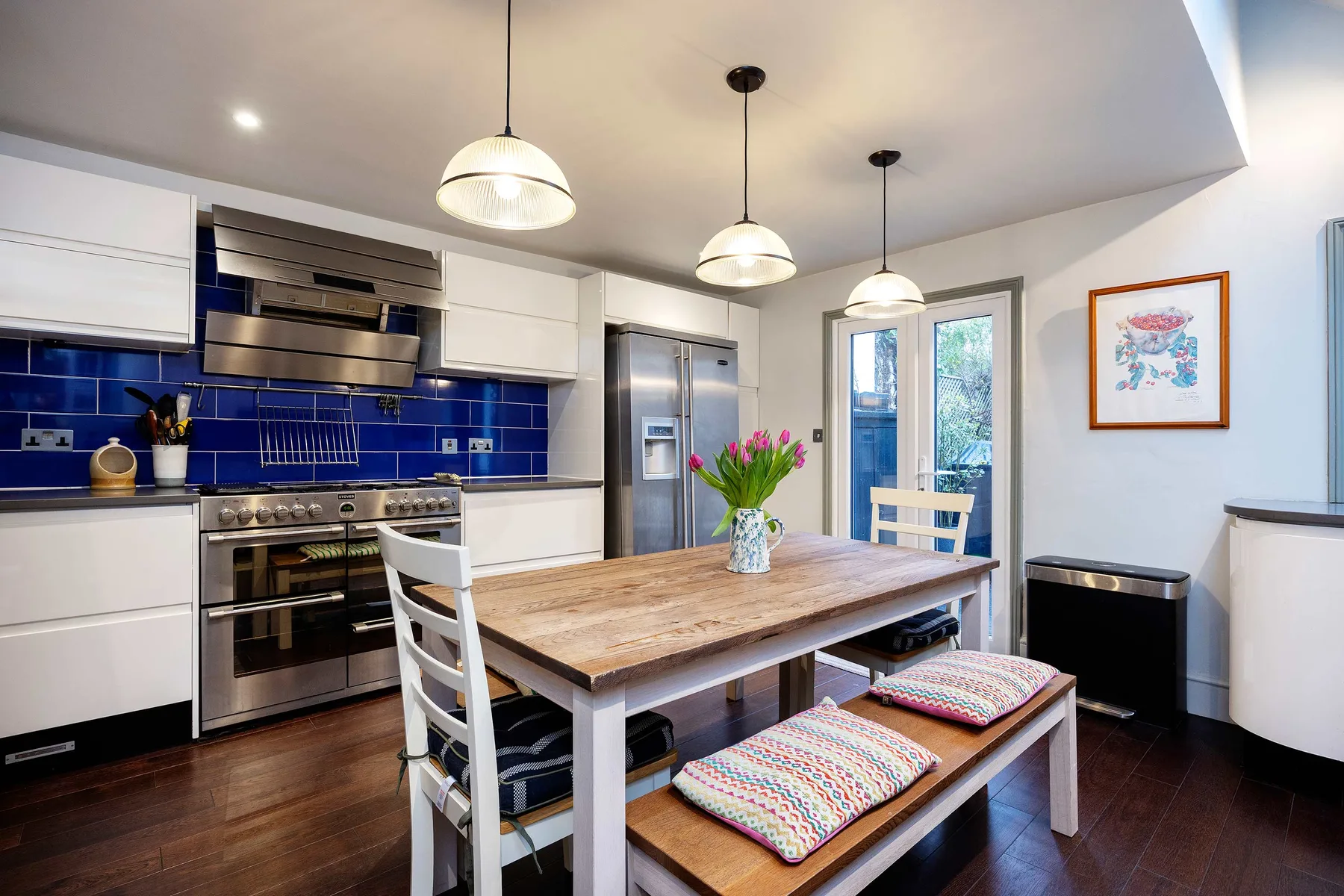 A kitchen and dining area with a wooden table and blue tile backsplash.