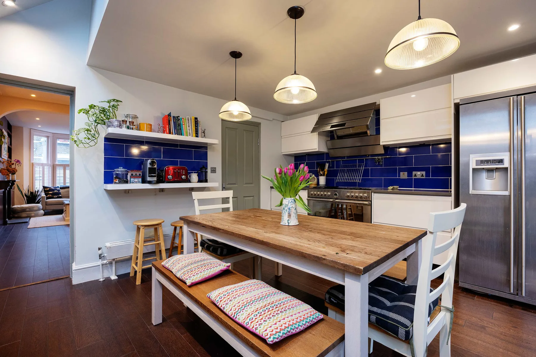 A kitchen and dining area with a wooden table and blue tile backsplash.
