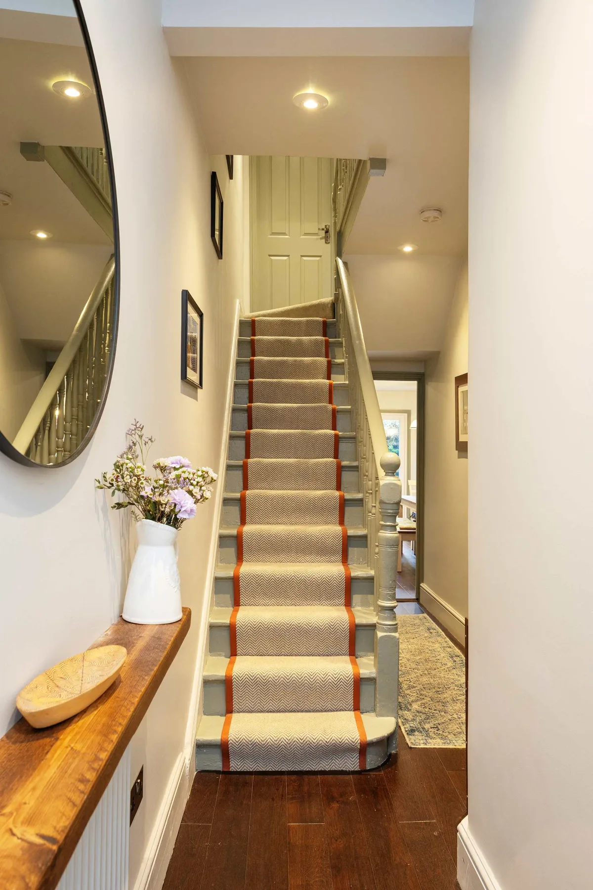 A carpeted staircase with striped edges leads up through a narrow hallway.