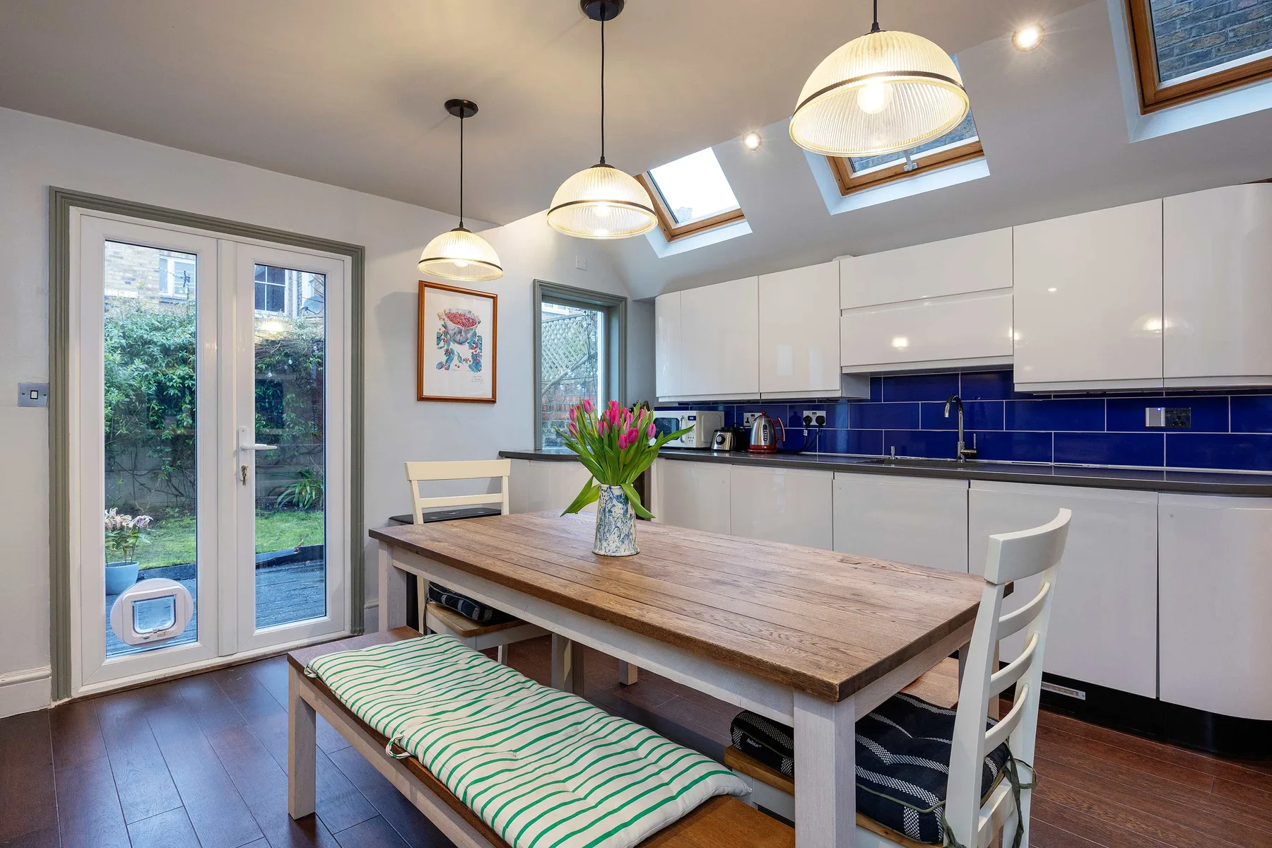 A bright kitchen and dining area with white cabinetry and a wooden table.
