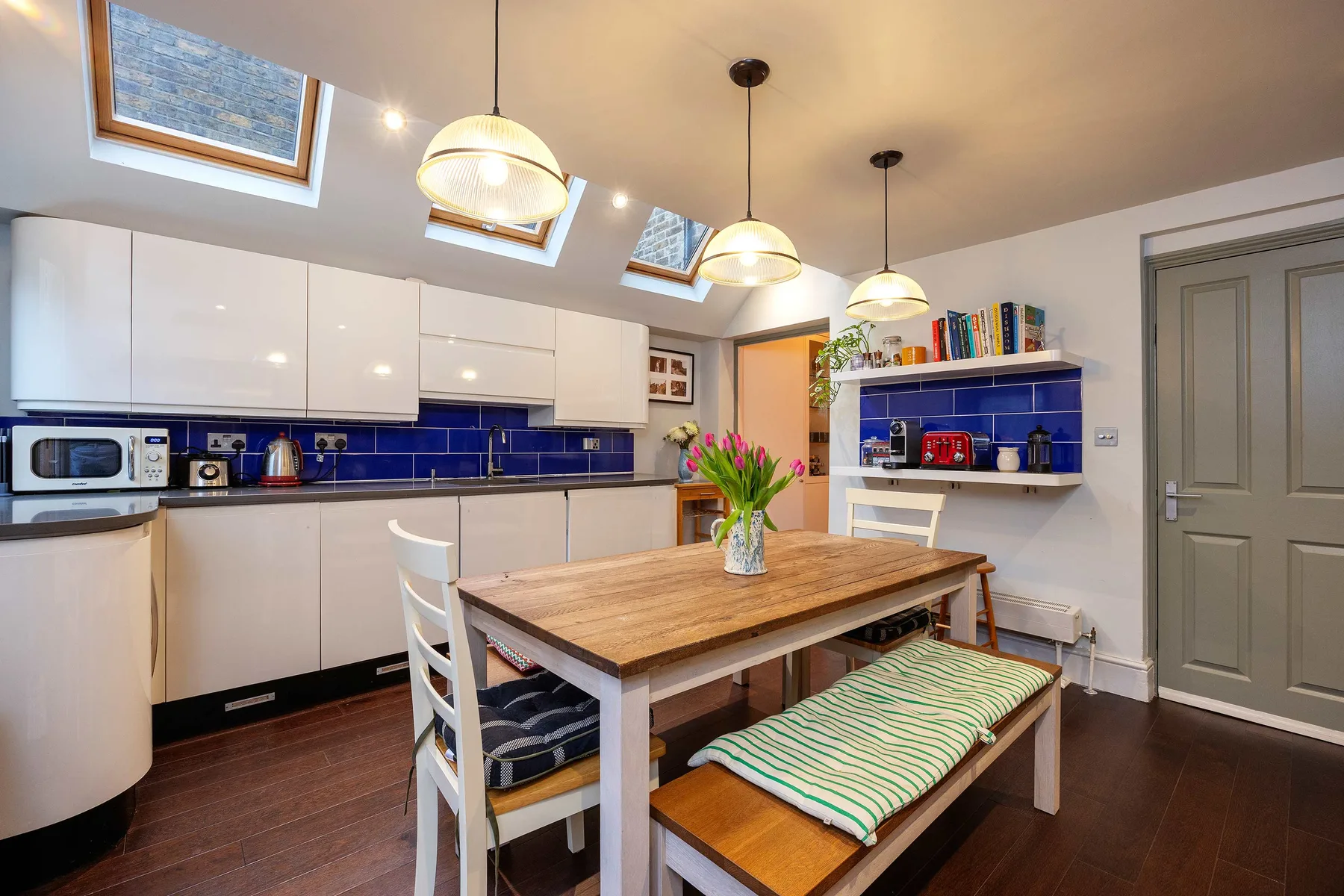A bright kitchen dining area with a wooden table and built-in shelves.