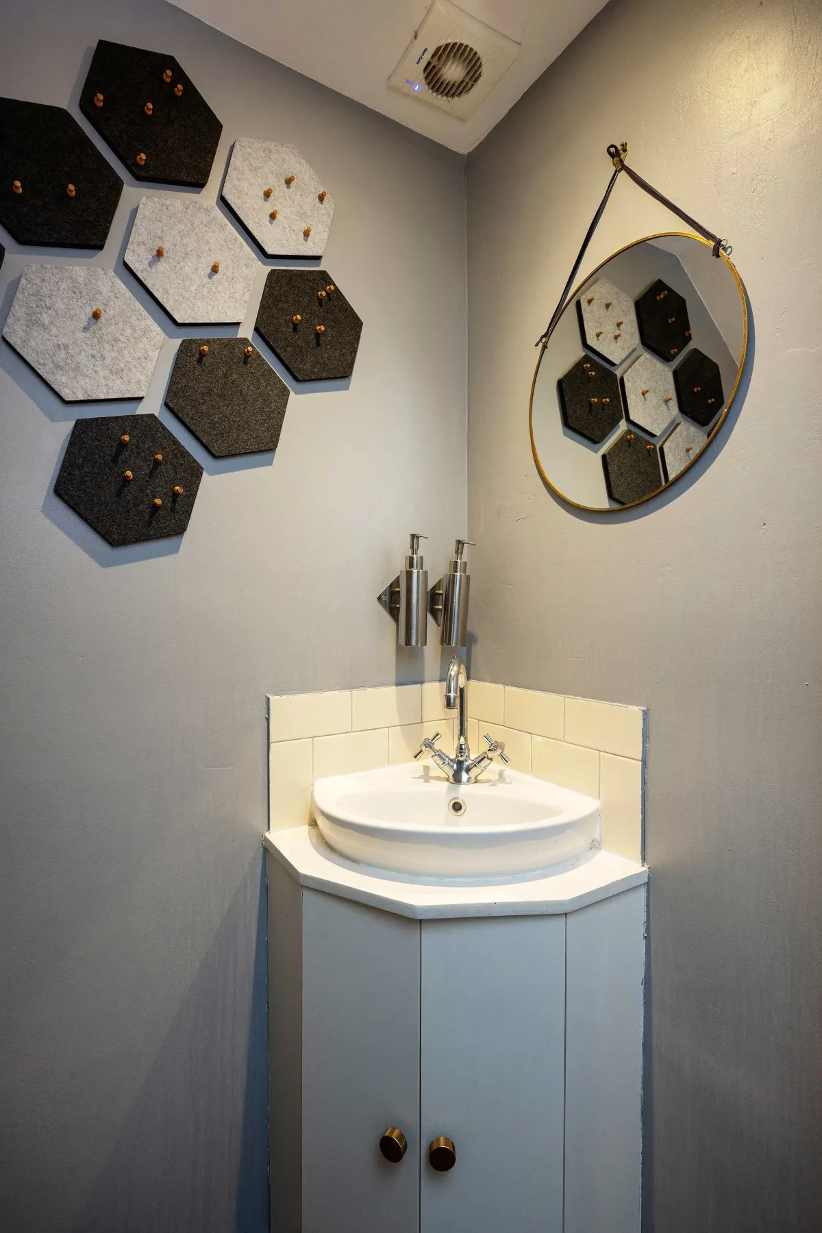 A compact bathroom vanity with a round basin, mirror, and geometric wall decorations.
