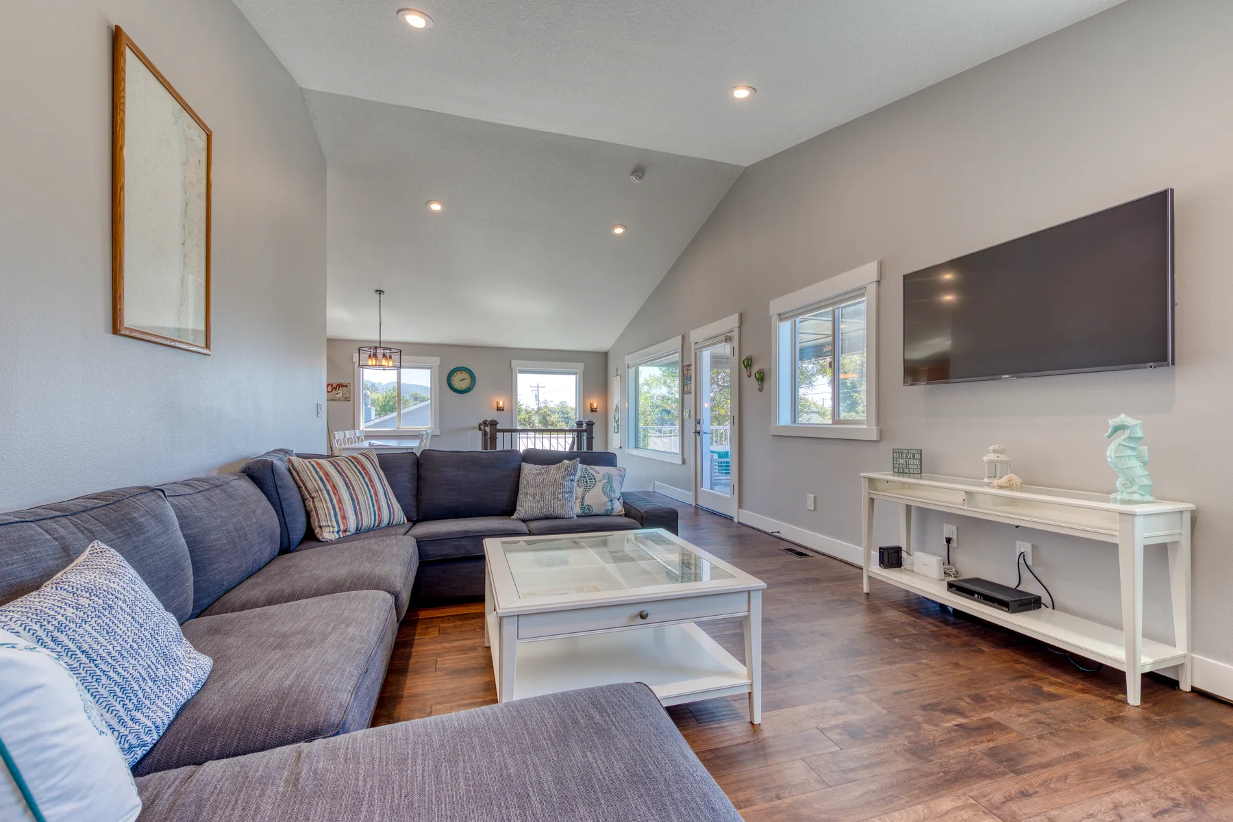 A bright living room with sectional seating, a coffee table, and a wall-mounted television.