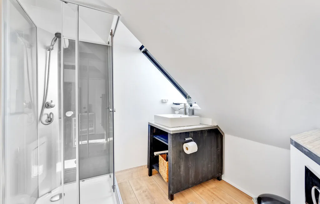 Un baño luminoso con ducha de vidrio y lavabo con mueble.