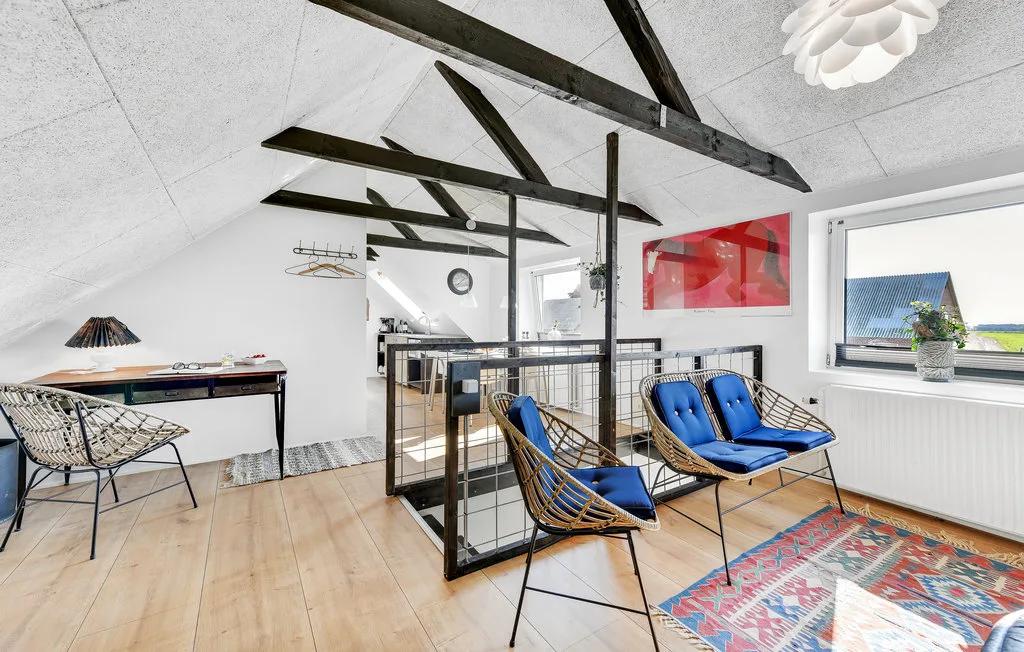 Una luminosa zona de estar tipo loft con cojines azules junto a una ventana grande.