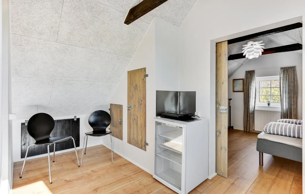 Una luminosa zona interior con dos sillas y un televisor junto a un dormitorio.