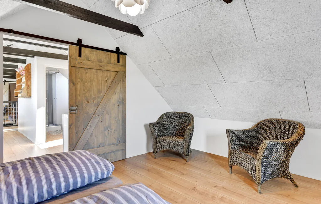 Una habitación luminosa con una puerta corredera de madera y dos asientos de mimbre.