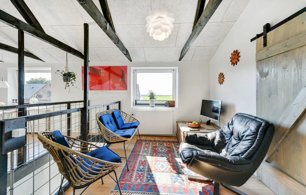 Una sala tipo loft con asientos azules, una alfombra estampada y una ventana.