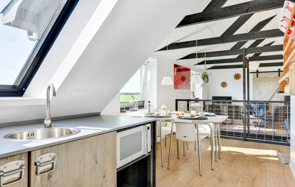Cocina abierta y comedor con una mesa bajo vigas expuestas.