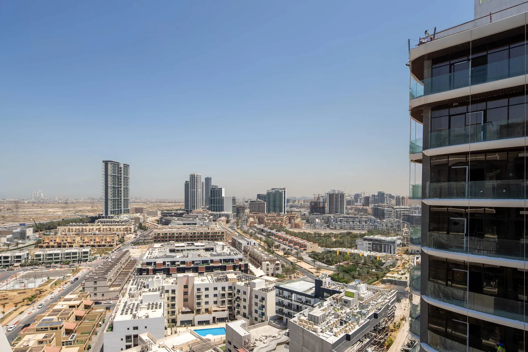 Cityscape view from a high-rise, with buildings and roads under a clear sky.
