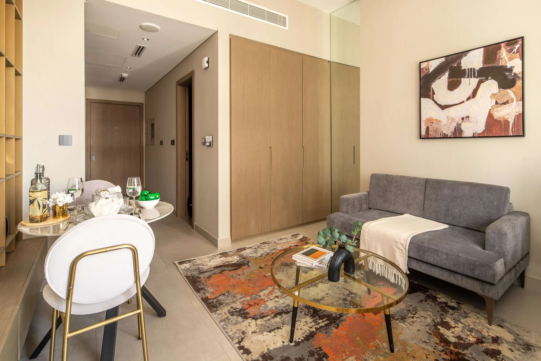 A living room with gray seating, a round coffee table, and abstract wall art.