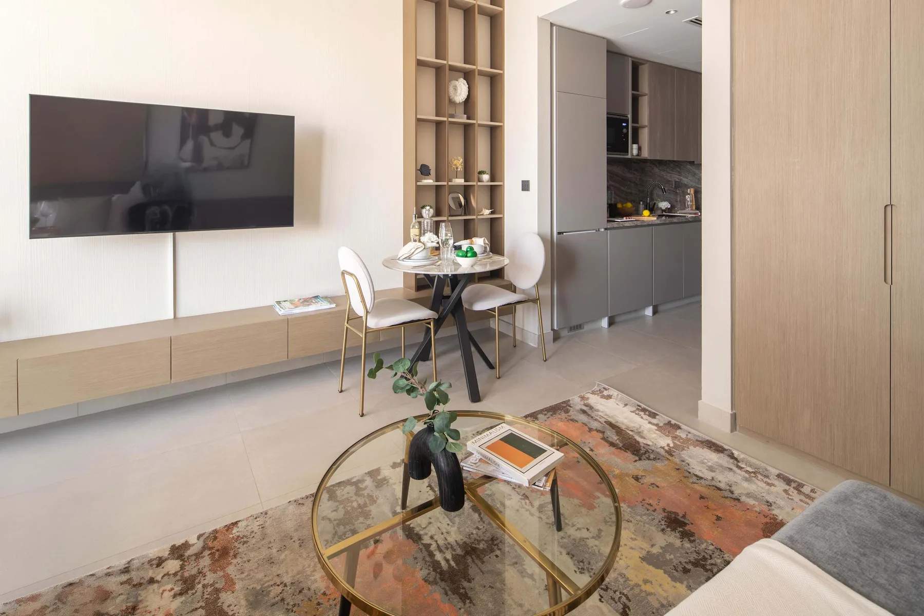 A modern living and dining area with a wall-mounted television and round glass coffee table.