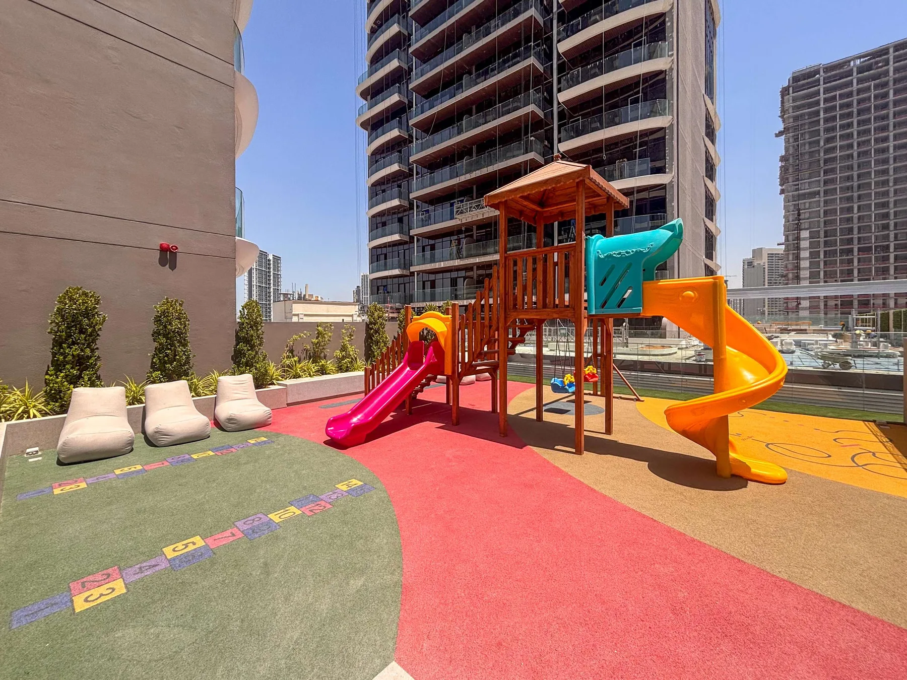 A rooftop playground features a colorful play structure with slides and soft ground surfacing.
