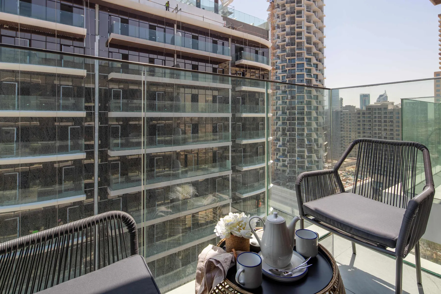 A balcony seating area overlooks neighboring high-rise buildings.
