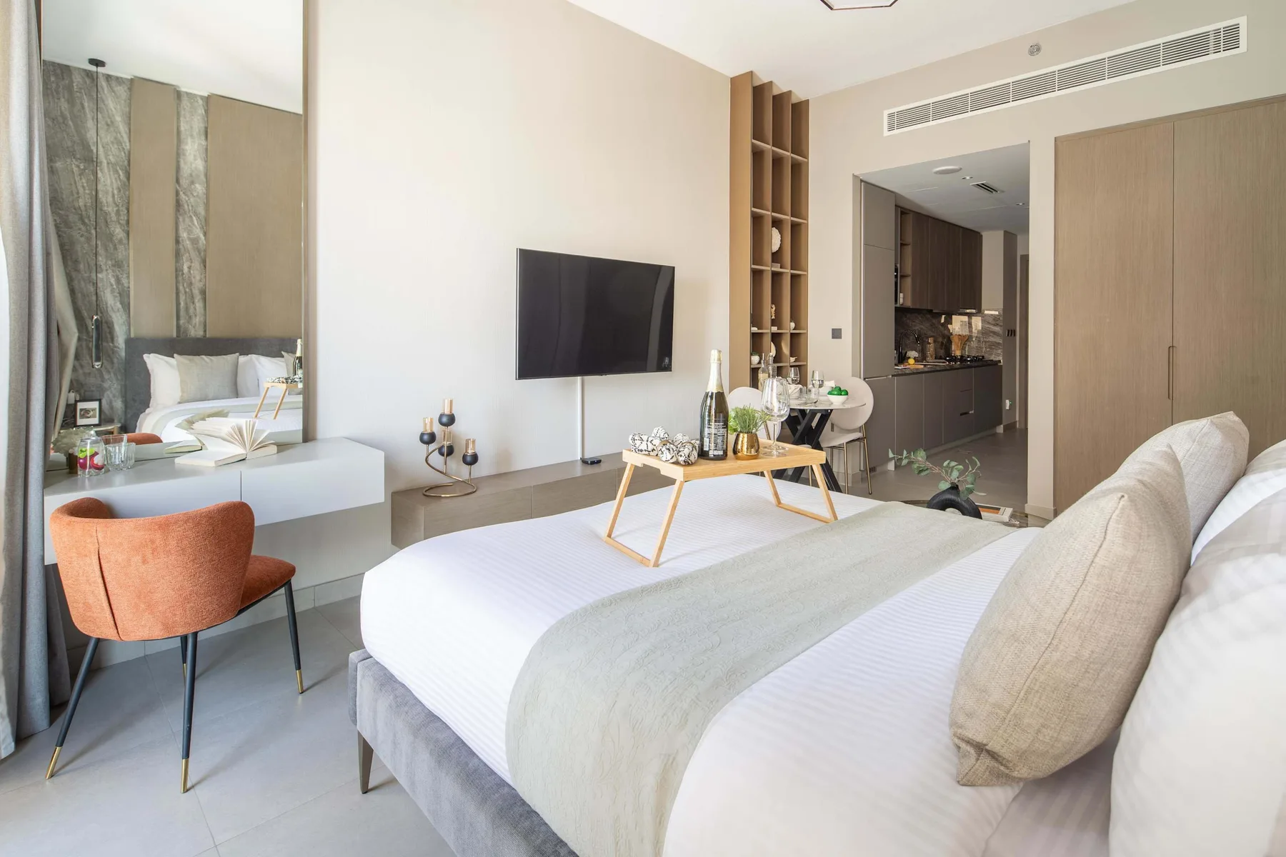A bright bedroom with a large bed and a television mounted on the wall.