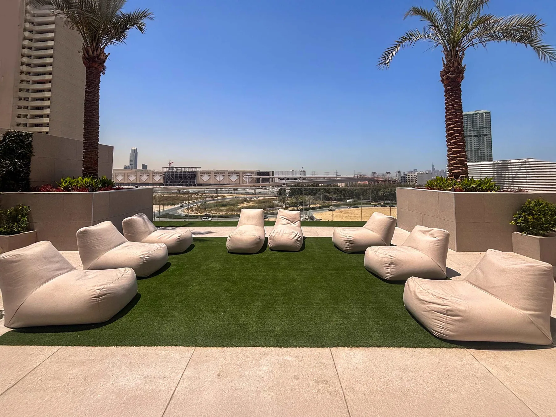 An outdoor terrace has cushioned seating arranged around a patch of green turf.