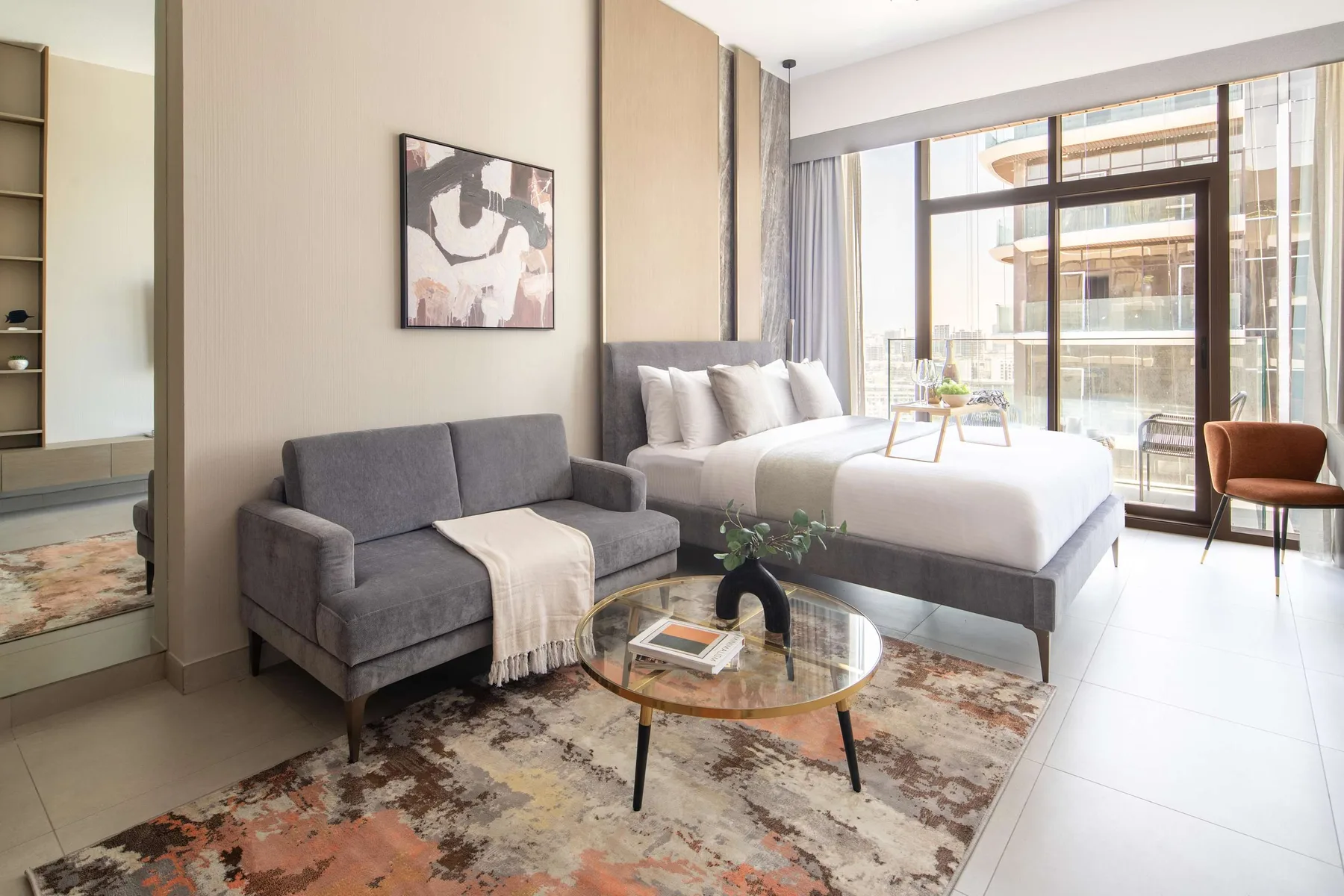 A bright bedroom with a bed, seating, and large windows.