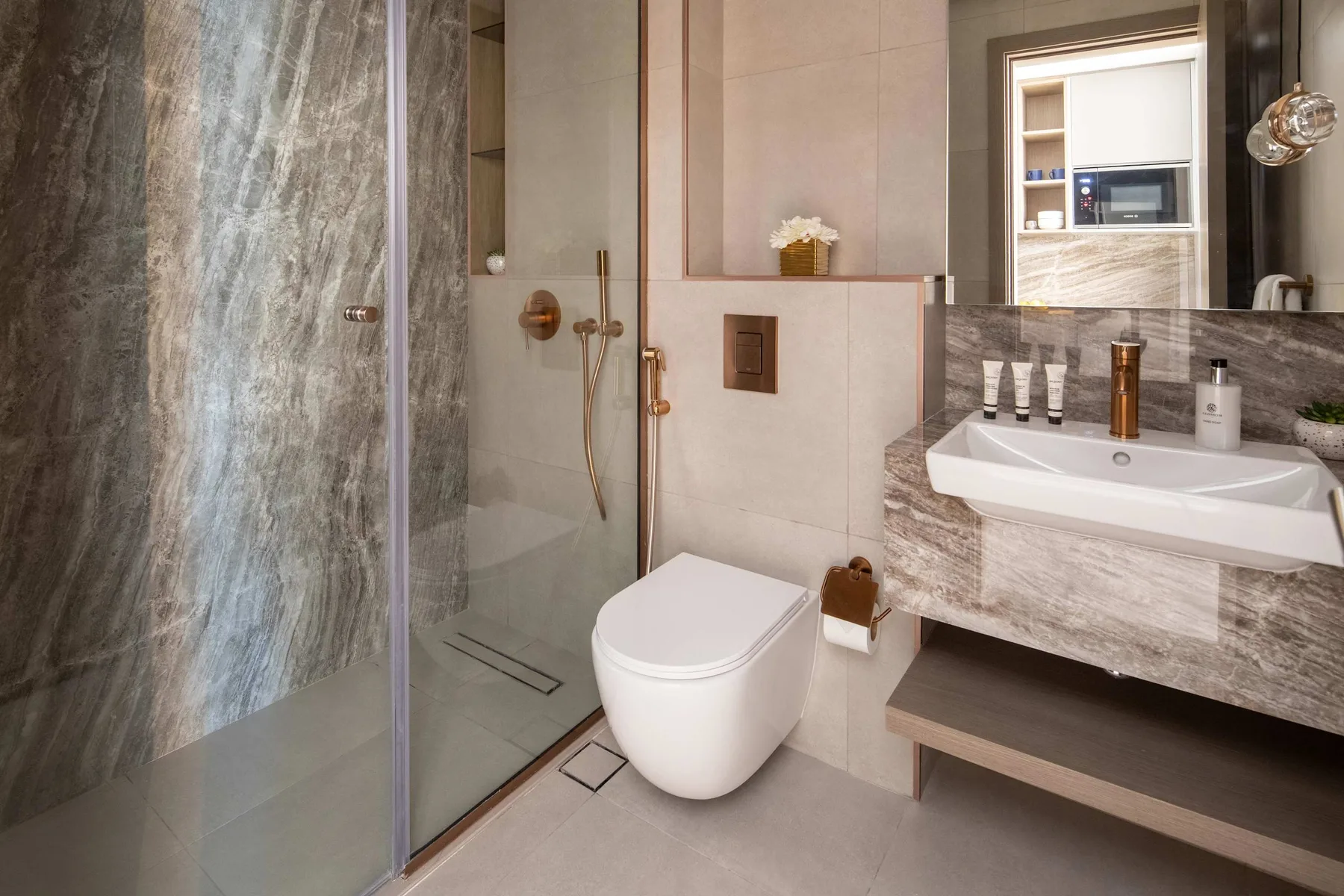 A modern bathroom with a glass shower, toilet, and wall-mounted sink.