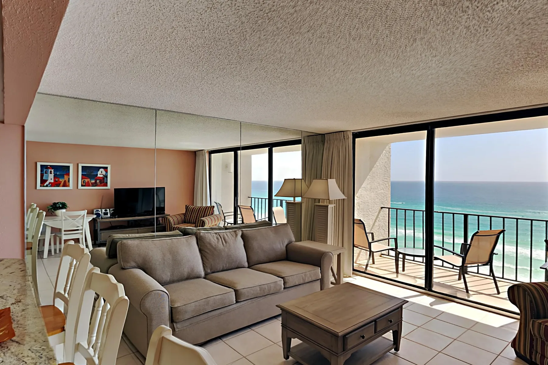 A living room with seating and a coffee table beside large windows overlooking the ocean.