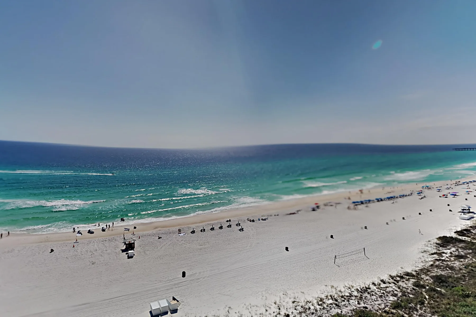 A sandy beach meets turquoise ocean waves beneath a clear sky.