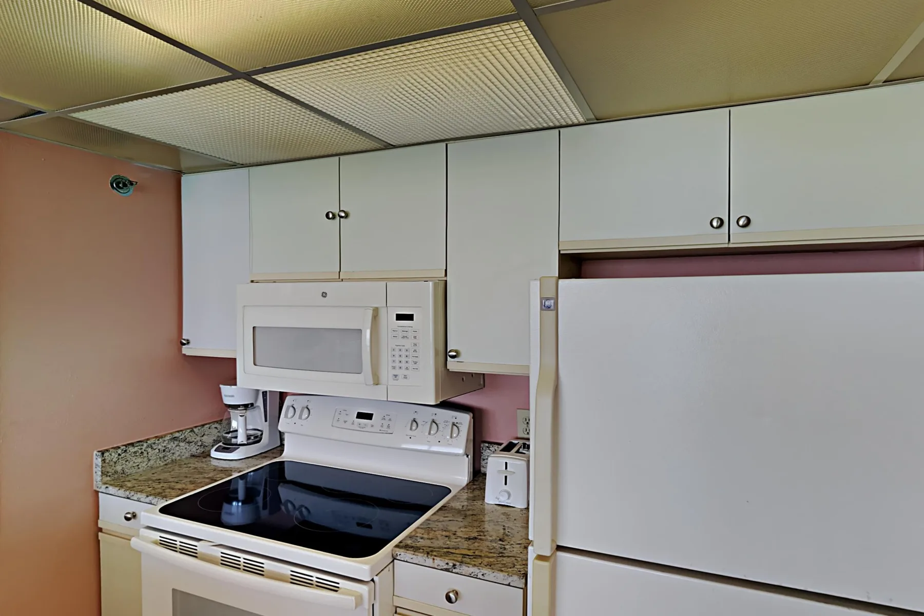 A kitchen with white cabinets, a microwave, and a stove.