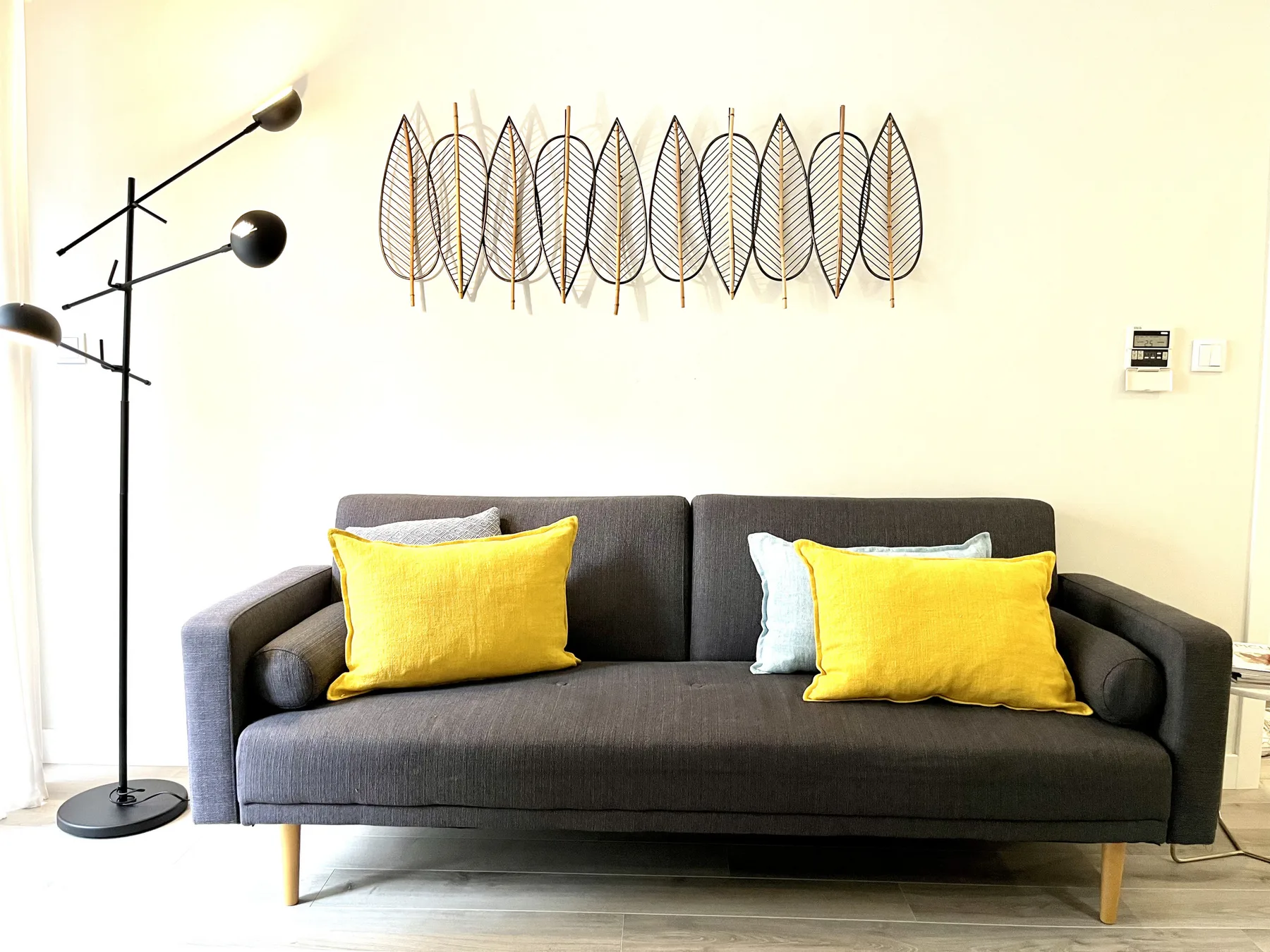 A living room with a dark sofa and bright yellow cushions.