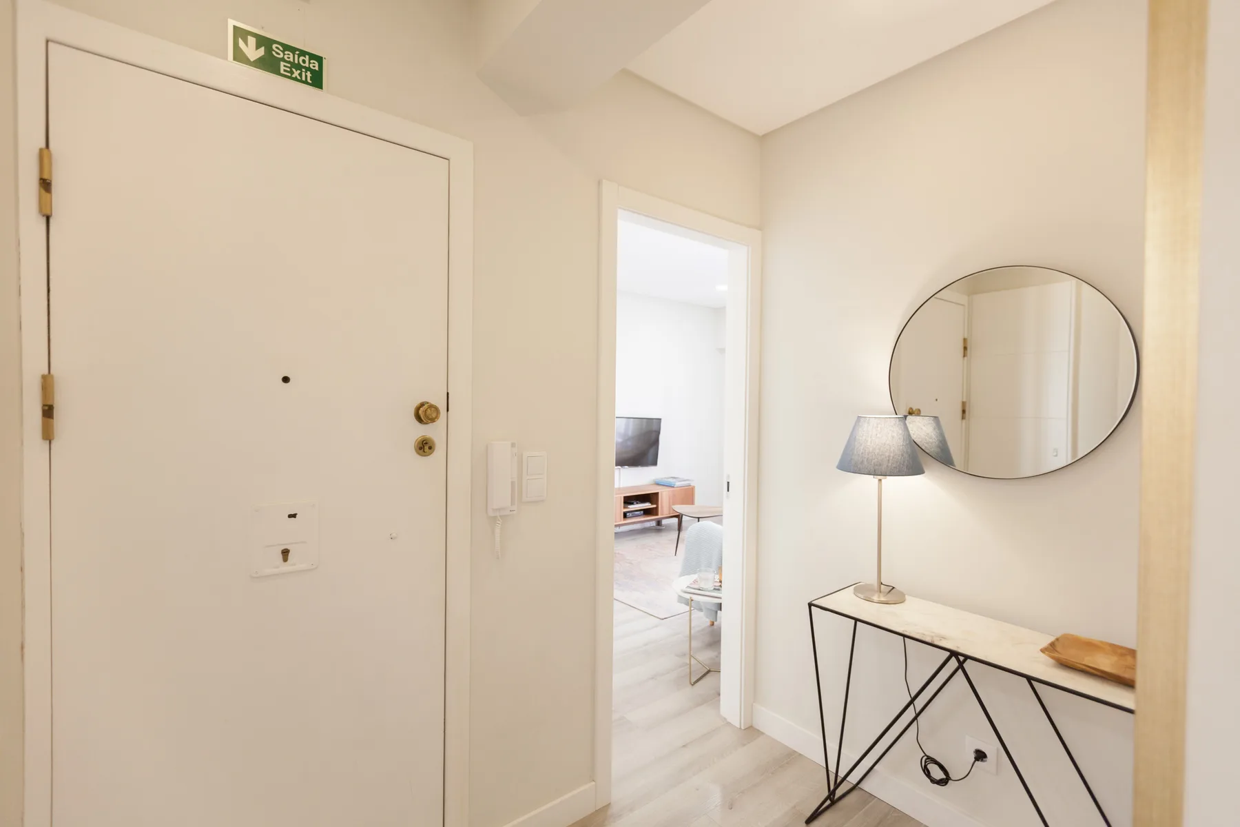 An apartment entryway with a console table and round wall mirror.
