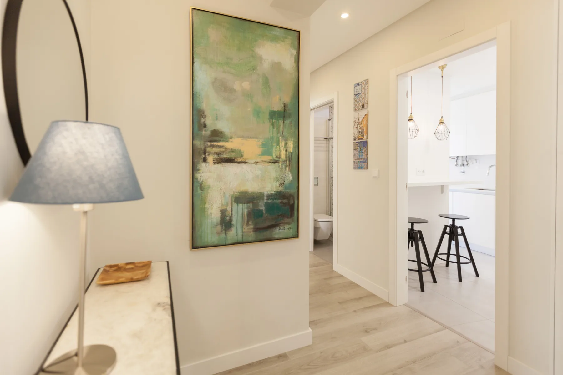 A bright apartment hallway opens into a kitchen with bar seating.