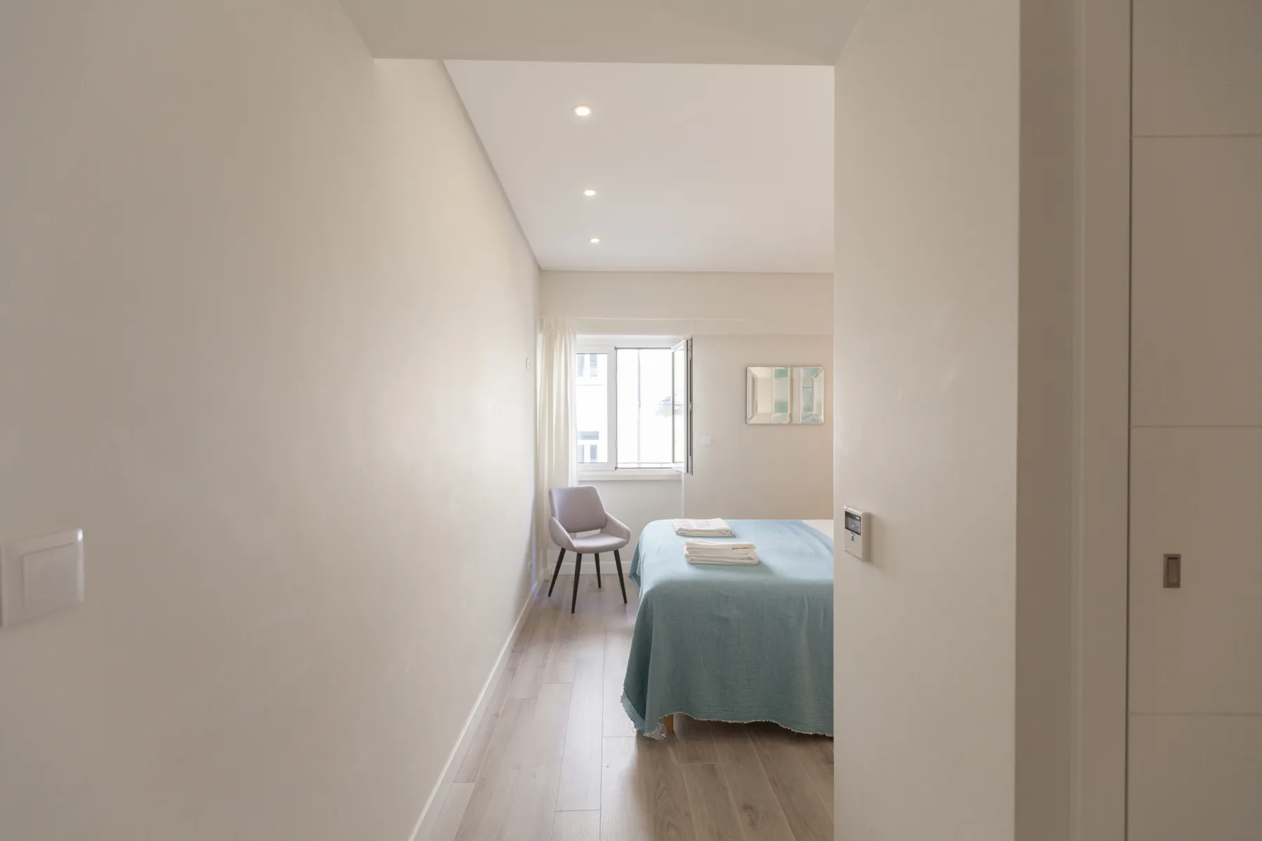 A bedroom with a bed and window at the far end.