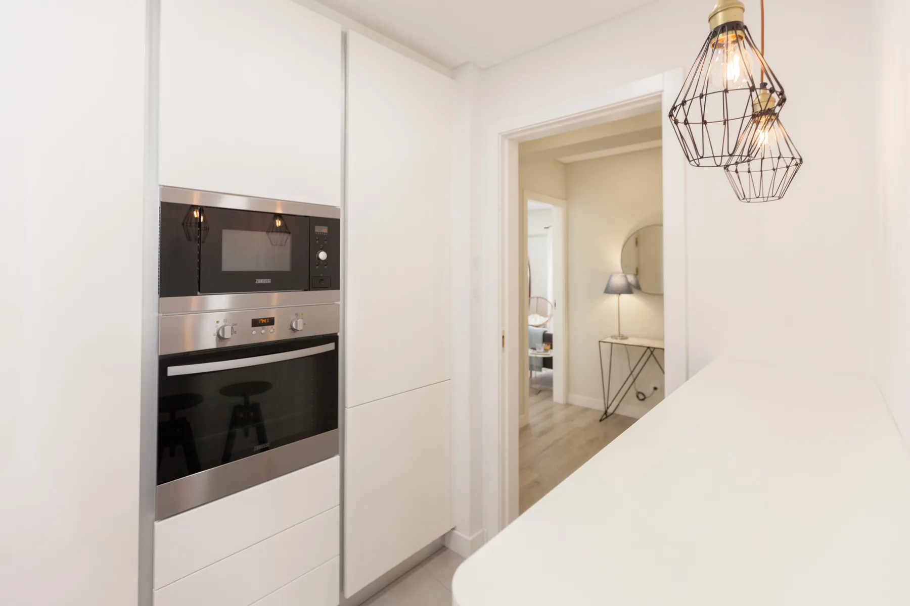 A bright kitchen with built-in appliances and a doorway to another room.