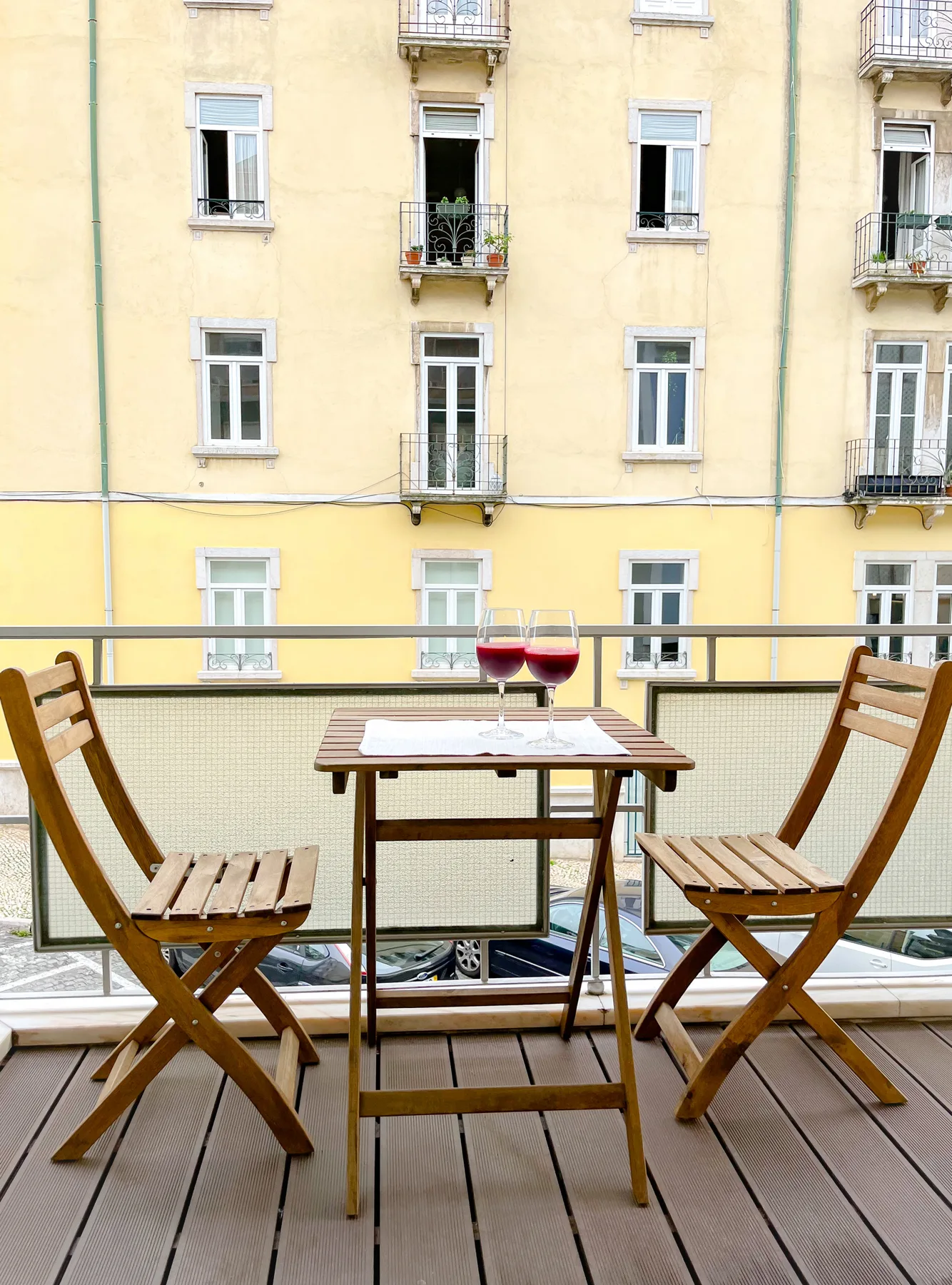 A balcony seating area with a table overlooks a yellow building.