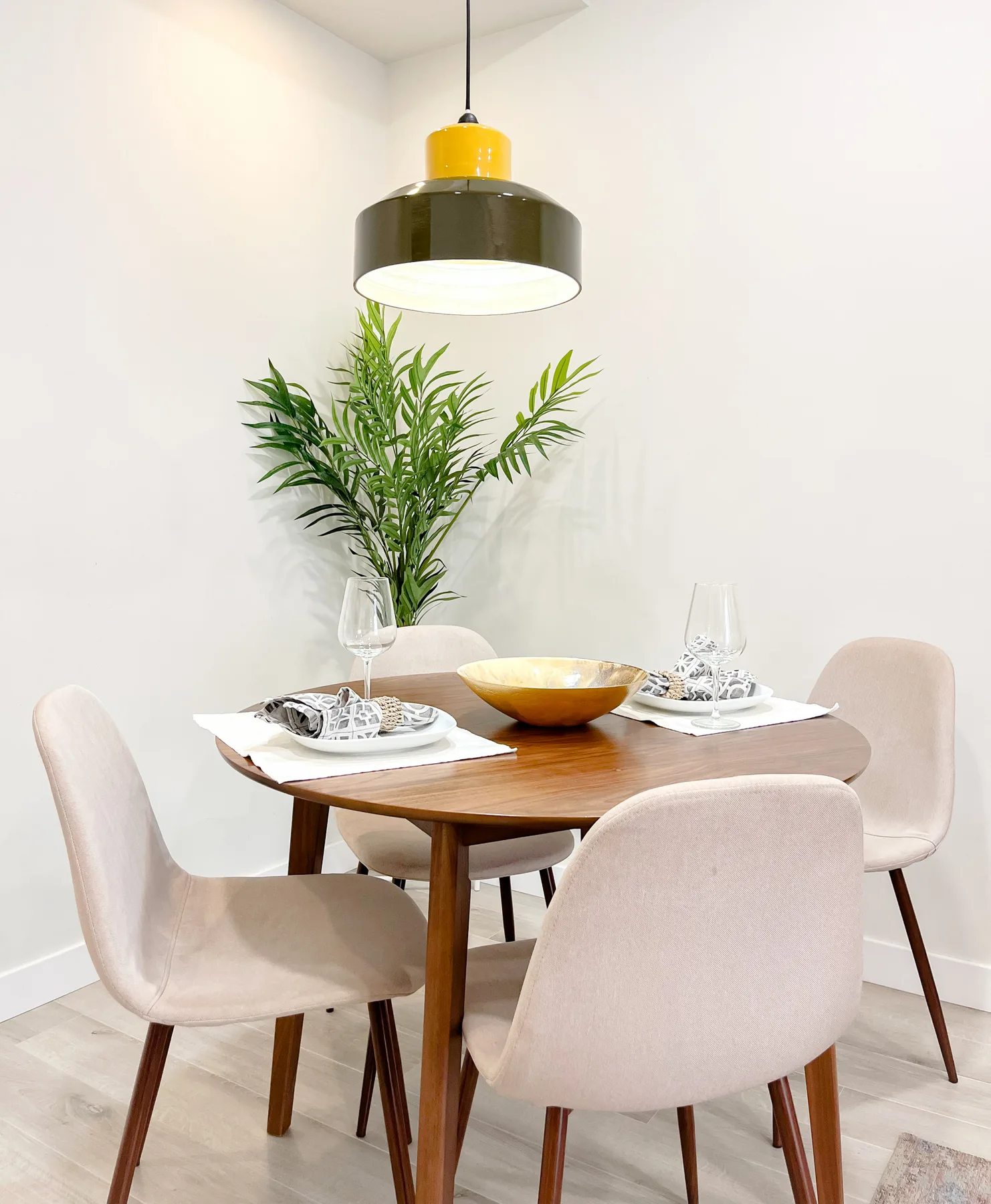 A dining area with a wooden table, upholstered seating, and a leafy plant.