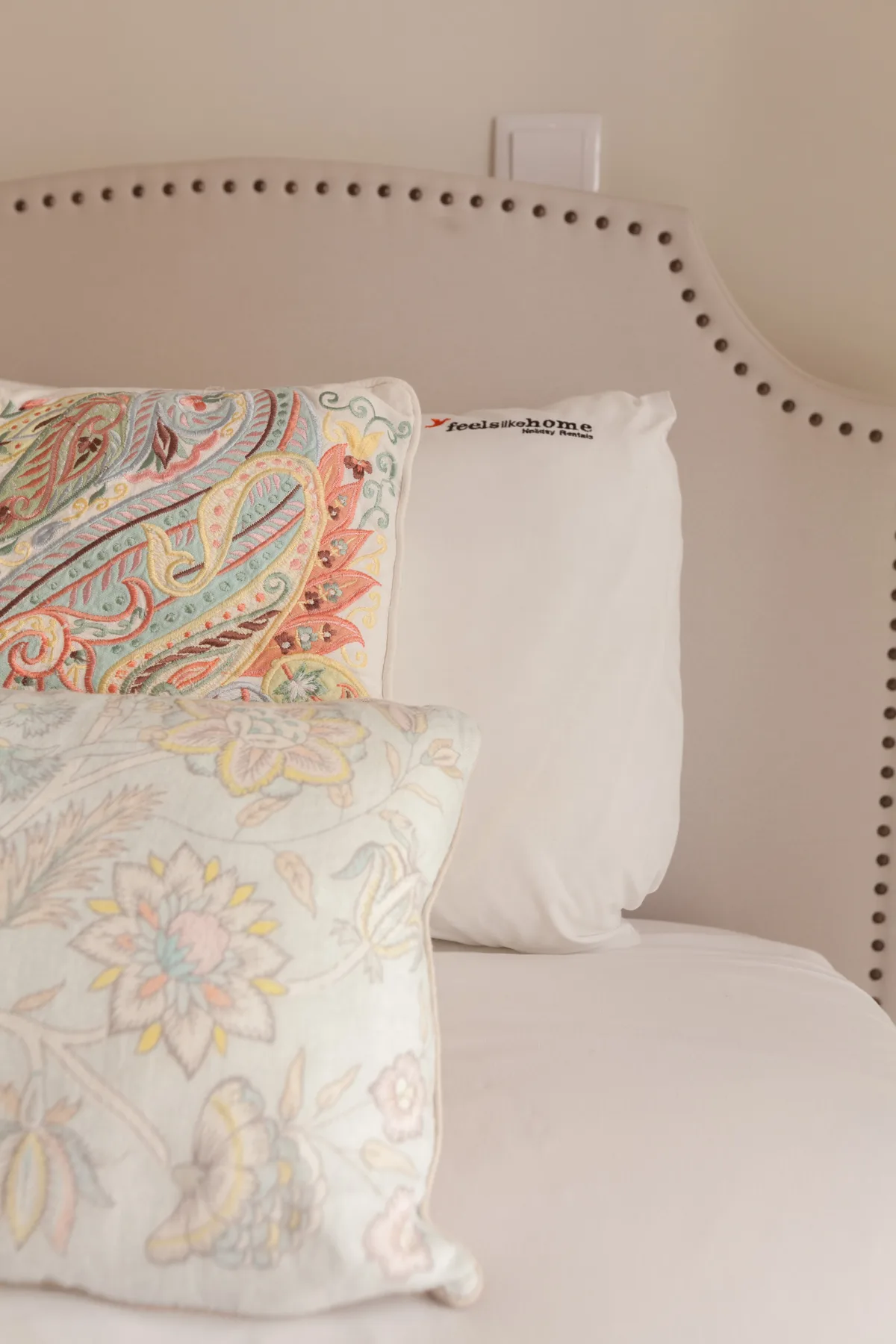 A bed with white bedding and patterned decorative pillows.