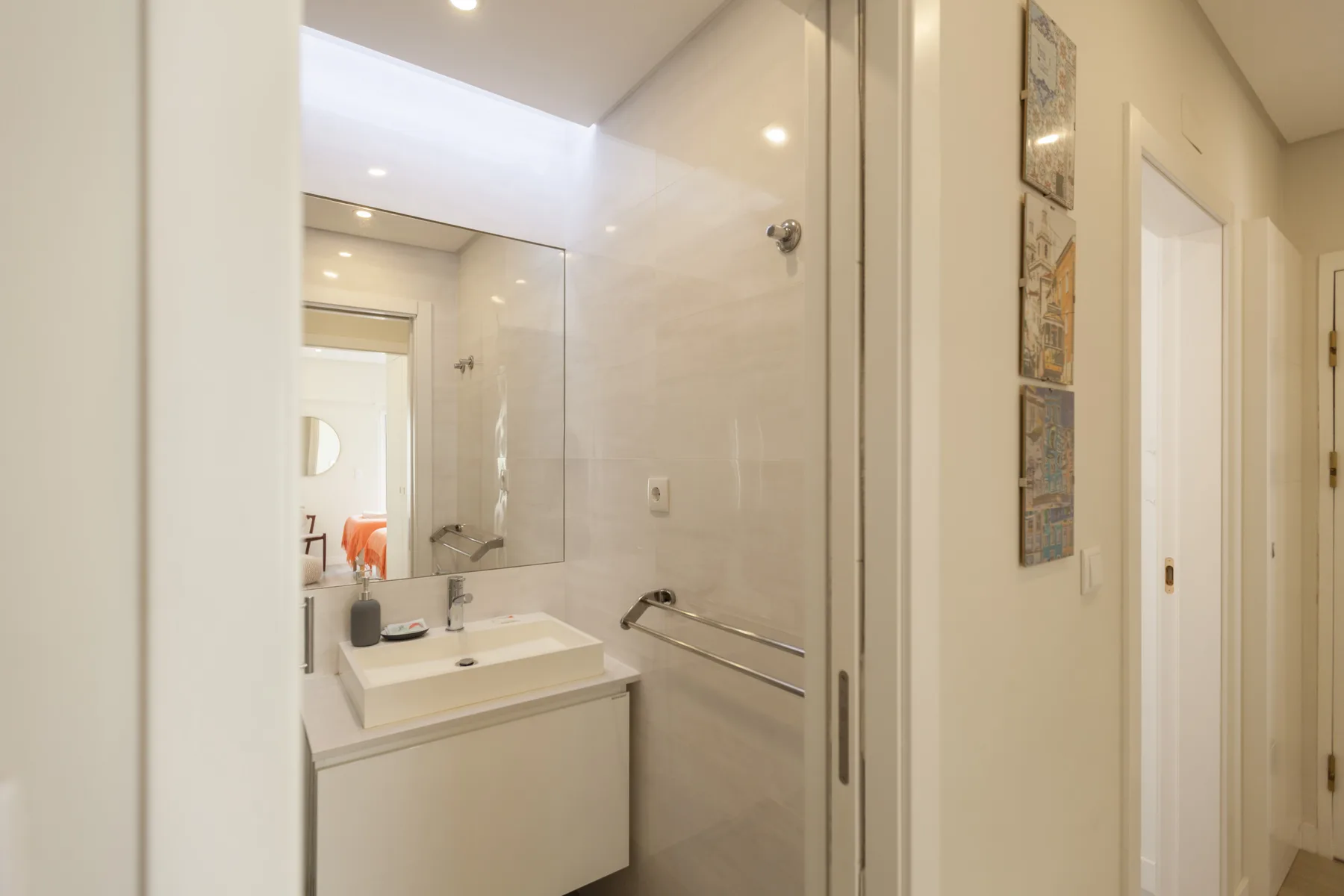 A bright bathroom with a sink, mirror, and glass shower enclosure.