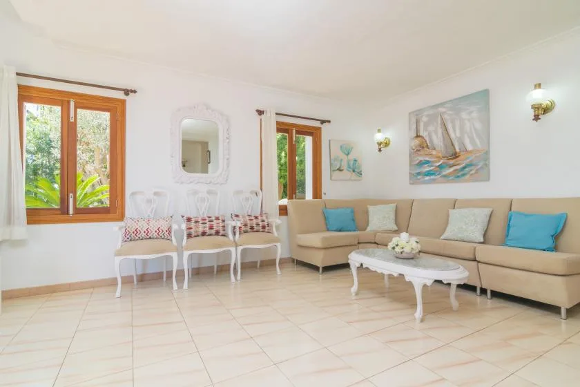 Una sala luminosa con asientos, una mesa de centro y ventanas.