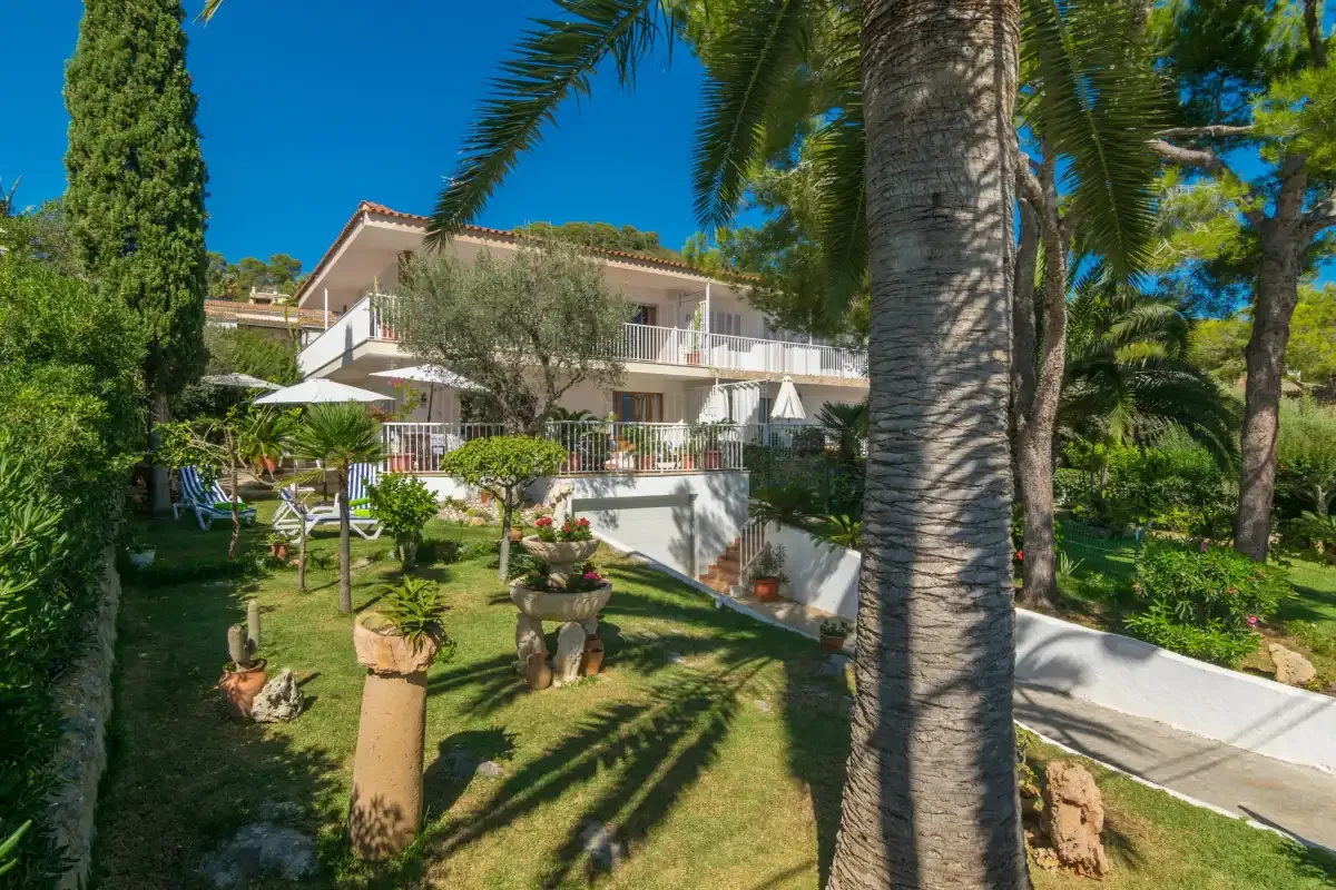 Un edificio blanco se encuentra entre palmeras y jardines.