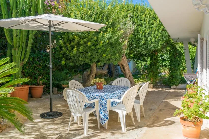 Una zona de comedor al aire libre con mesa, asientos y una gran sombrilla.