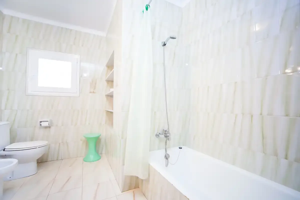 Un baño luminoso con bañera, ducha e inodoro.