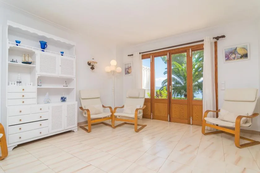 Una sala de estar luminosa con asientos claros y puertas acristaladas con marco de madera.