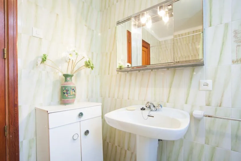 Un baño con un lavabo de pared y un espejo encima.