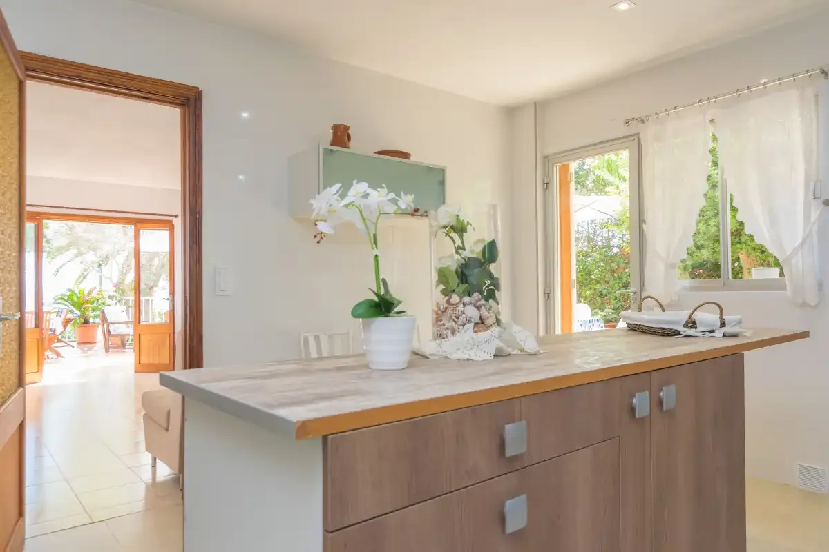 Una cocina luminosa con una isla amplia y ventanas con vistas a la vegetación.