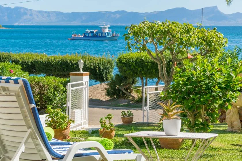 Una zona de descanso en el jardín da al mar, con un barco a lo lejos.