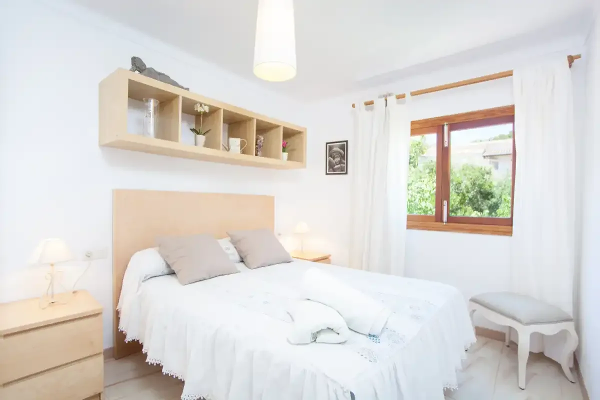 Un dormitorio luminoso con una cama doble y una ventana con vistas a la vegetación.