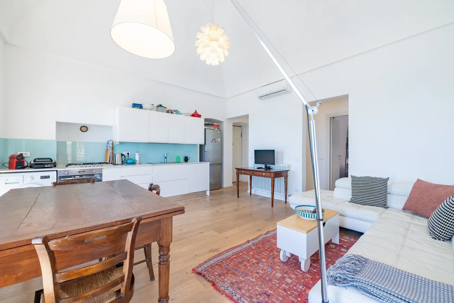 A bright open-plan living room and kitchen with a dining table and seating.
